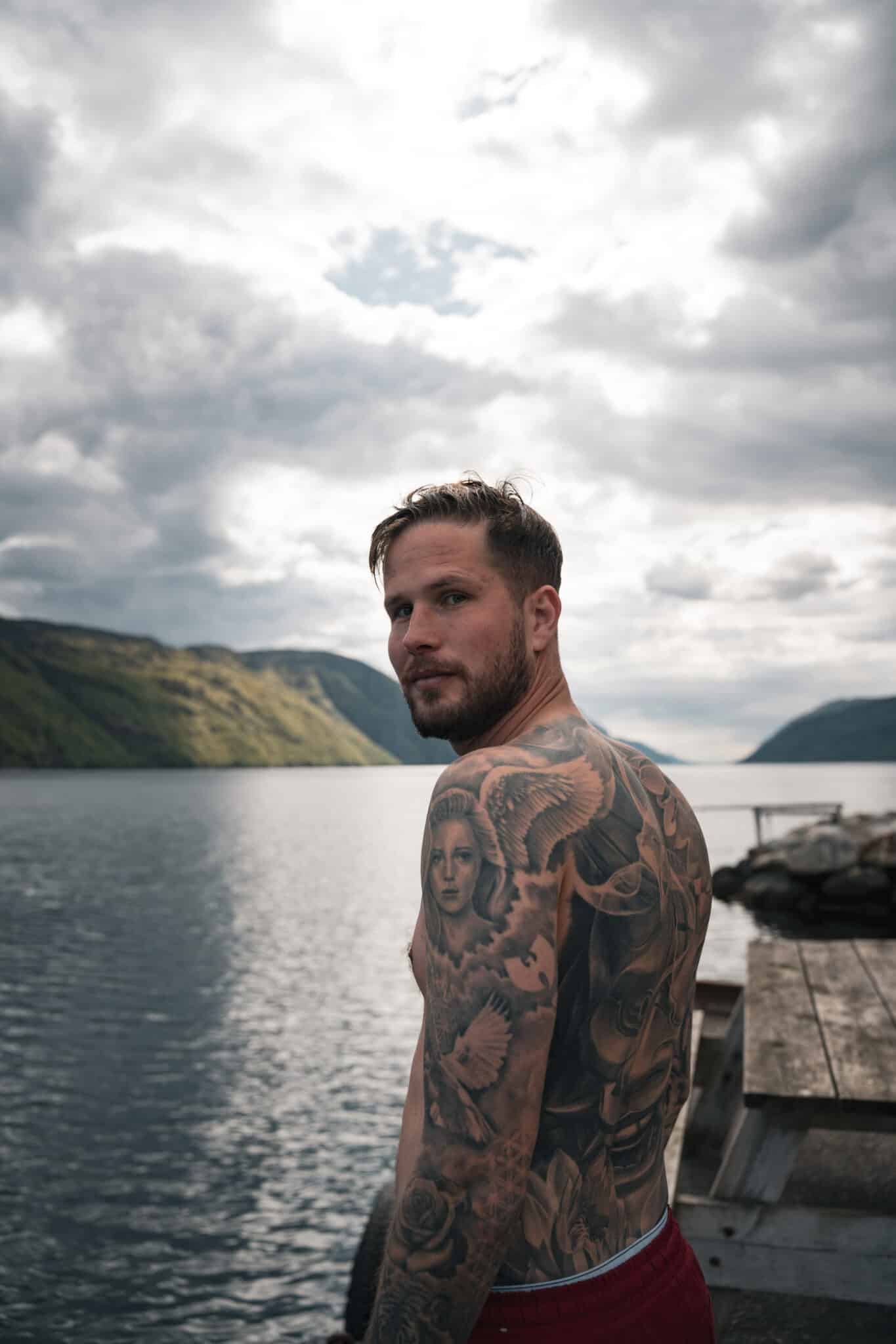 Jesper Hedlund looking over his shoulder beside water and mountains.