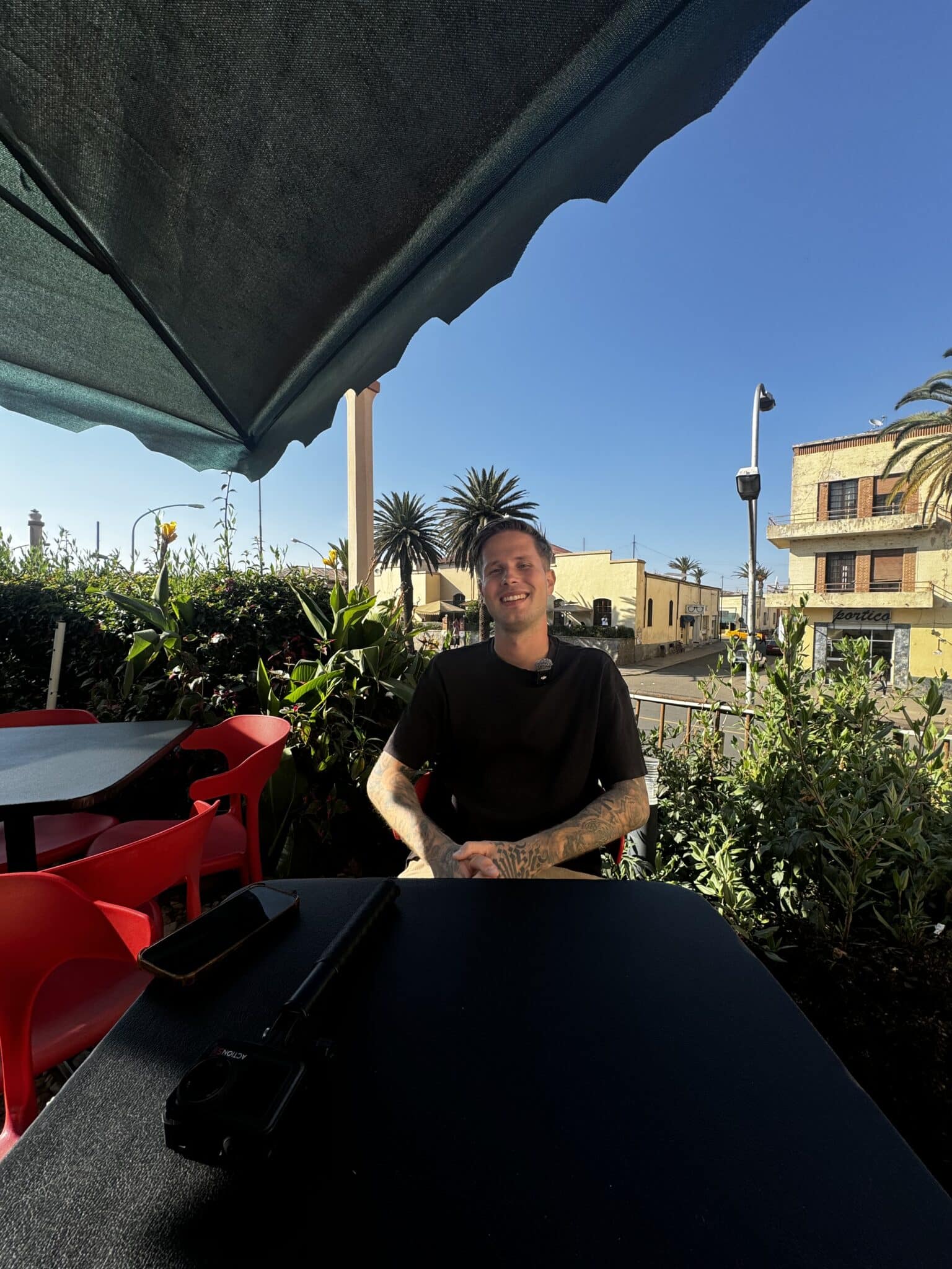 Jesper Hedlund seated at an outdoor café table beneath a parasol.
