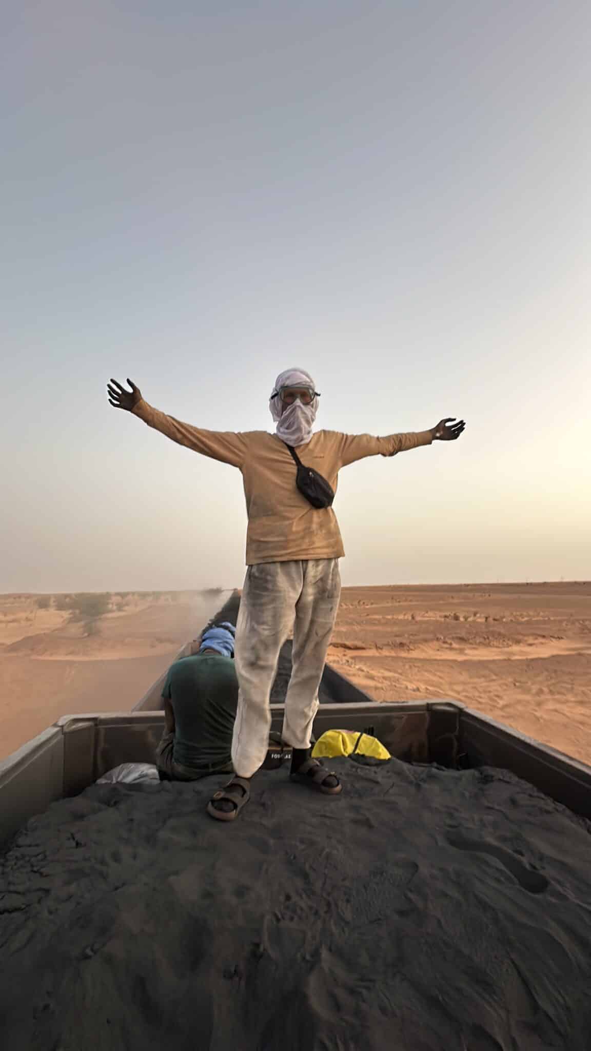 Jesper Hedlund standing on a freight train in the desert with his arms outstretched.