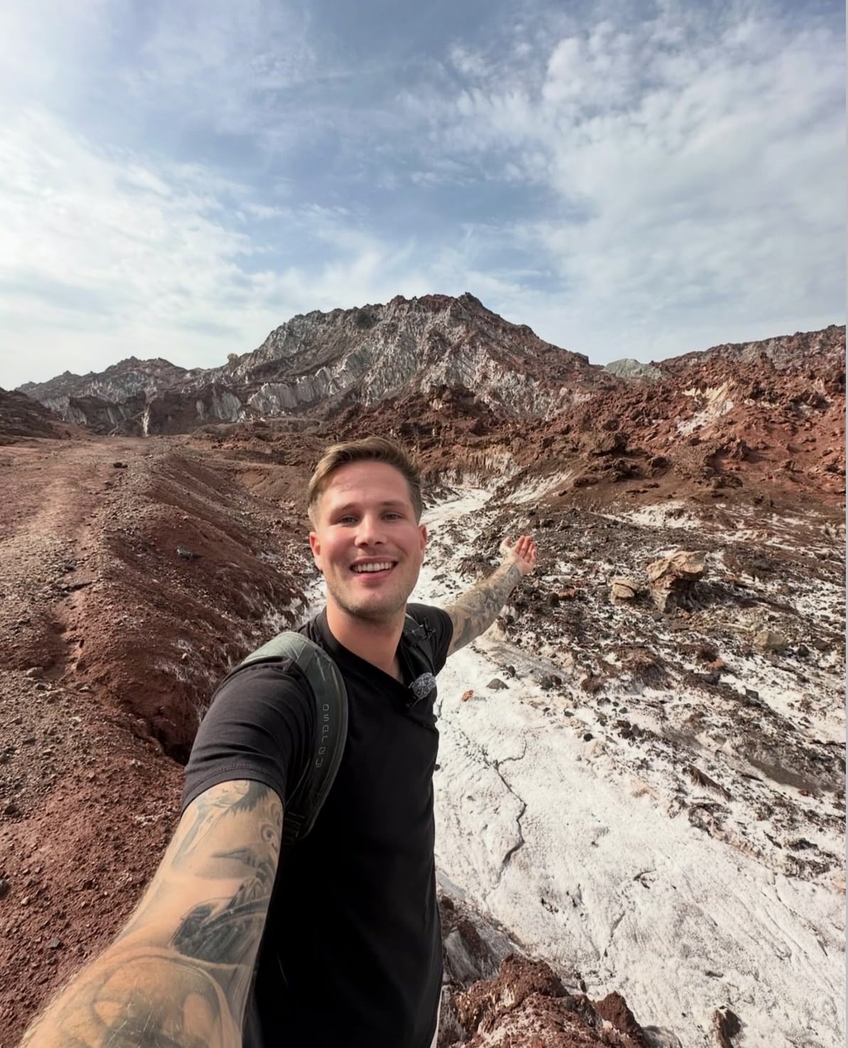 Jesper Hedlund smiling for a selfie in a rocky mountain landscape.
