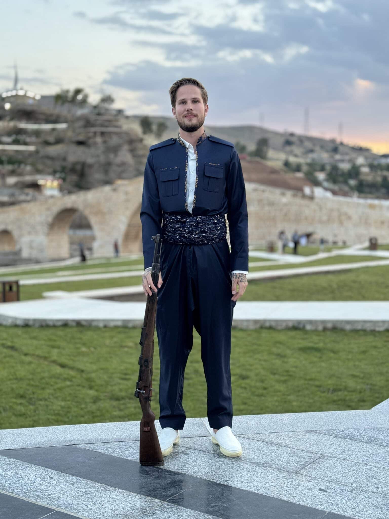 Full-length portrait of Jesper Hedlund in a blue outfit on a landscaped terrace.