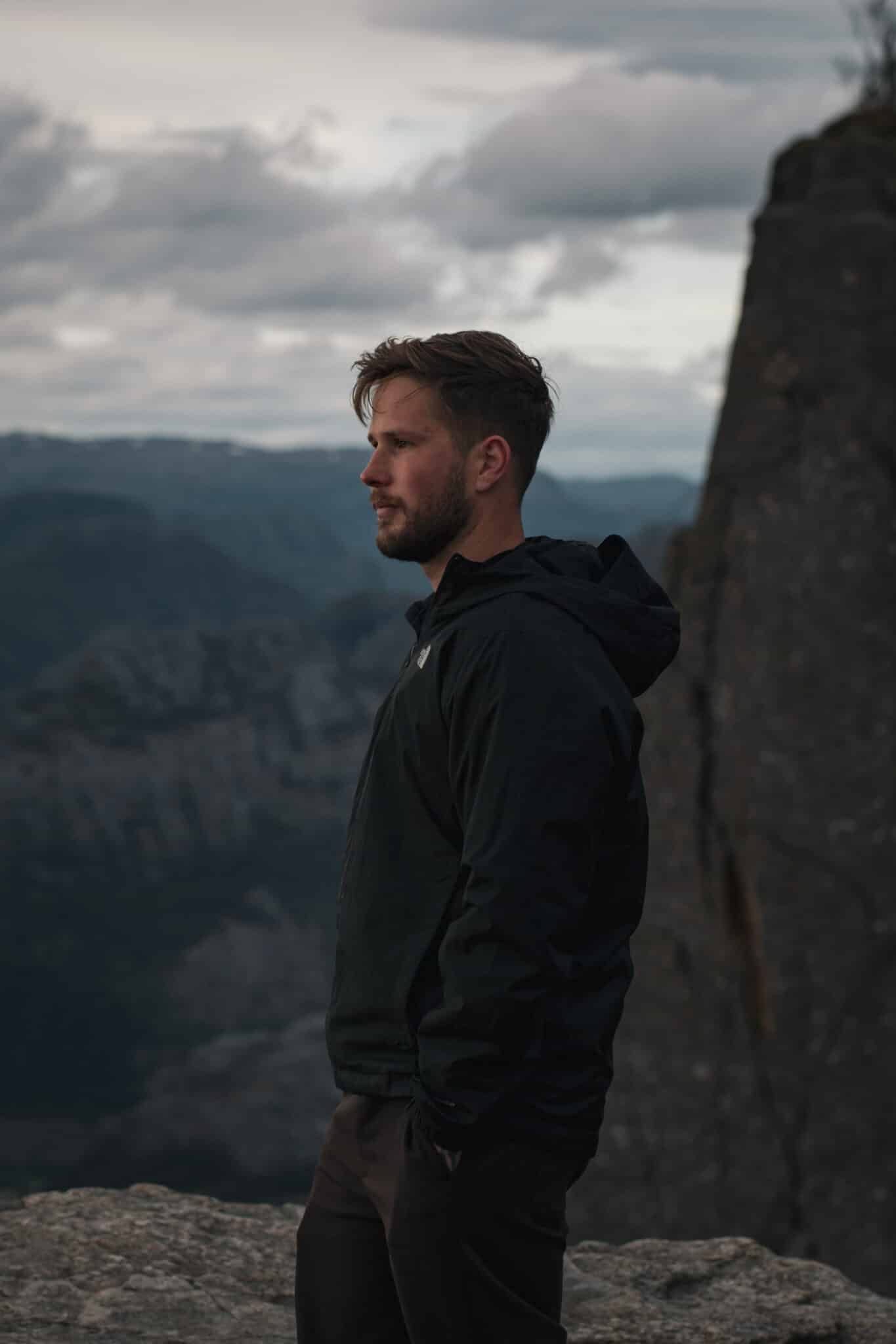 Jesper Hedlund in a dark jacket beside a steep mountain landscape.